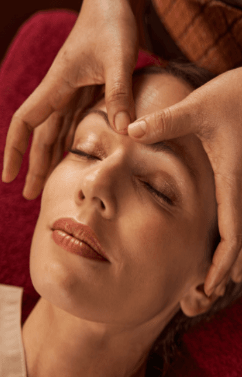 Woman receiving relaxing healing therapy massage on face, representing holistic healing therapies and wellness care