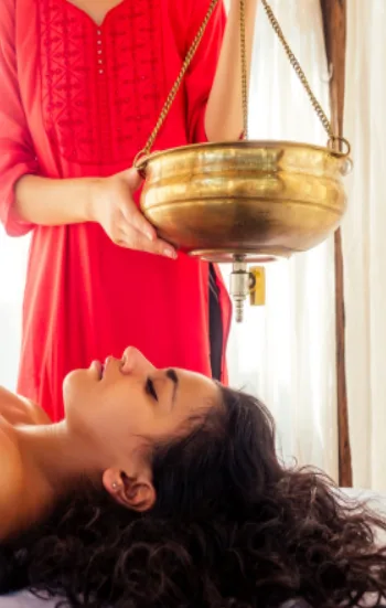 Ayurvedic shirodhara therapy being performed at a Panchakarma center, showing traditional oil pouring treatment for deep relaxation and holistic healing
